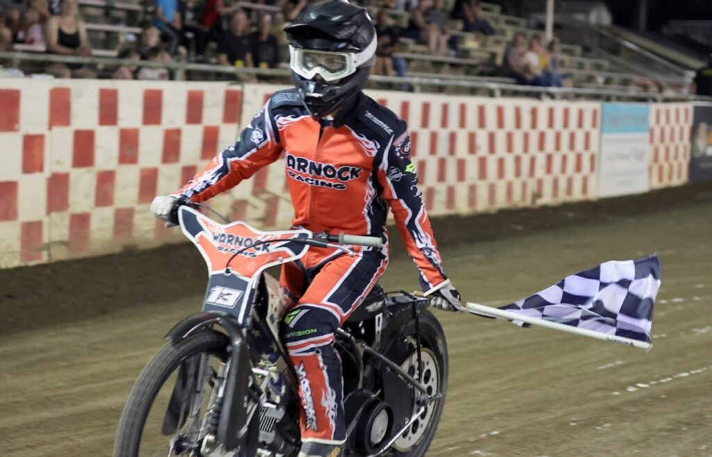 Jameson Hutchinson takes a victory lap with the checkered flag after winning the Youth 250cc main event. It was the Hutchinson's third main event win in a row. May 30 2025 - More great racing at Fast Friday’s Motorcycle Speedway in Auburn CA.