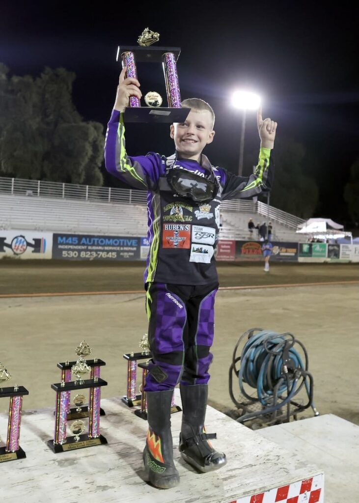 Luke Seeger holds his Youth 150cc D3 main event winner's trophy high after the races Friday night. June 26 2026 - 2026 Speedway & Team Challenge Round #3.